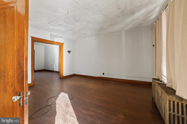 empty room featuring dark hardwood / wood-style flooring and radiator heating unit