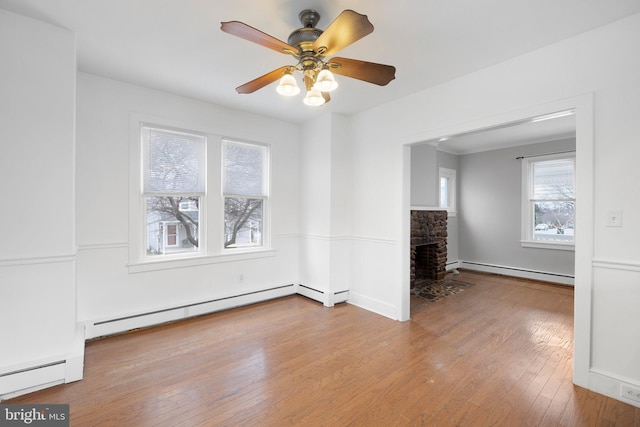 empty room featuring baseboard heating, ceiling fan, and light hardwood / wood-style floors