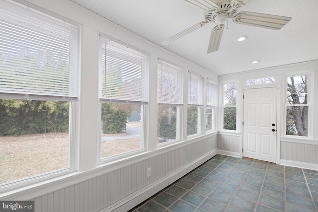 unfurnished sunroom with ceiling fan, a healthy amount of sunlight, and a baseboard heating unit