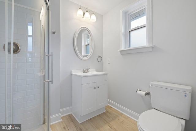 bathroom with hardwood / wood-style flooring, vanity, a shower with shower door, and toilet