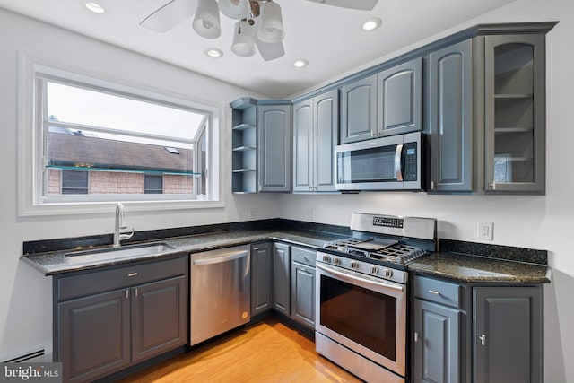 kitchen featuring ceiling fan, sink, baseboard heating, appliances with stainless steel finishes, and light wood-type flooring