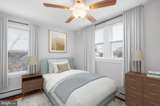 bedroom featuring baseboard heating, ceiling fan, and light hardwood / wood-style floors