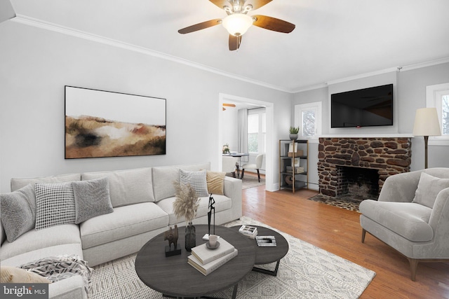 living room with a fireplace, hardwood / wood-style floors, ceiling fan, and ornamental molding