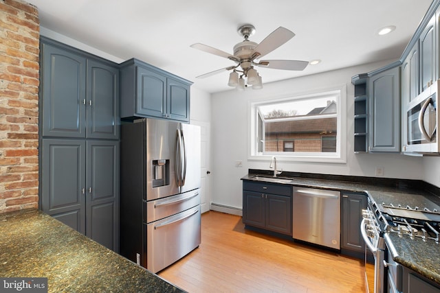 kitchen featuring ceiling fan, sink, baseboard heating, dark stone counters, and appliances with stainless steel finishes