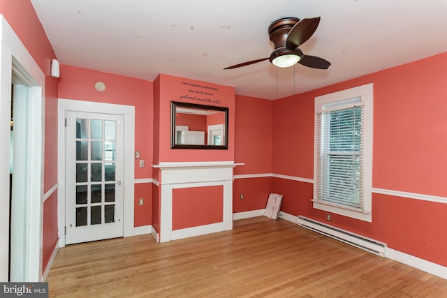 interior space with ceiling fan, a fireplace, light hardwood / wood-style floors, and a baseboard heating unit