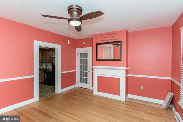 unfurnished room with ceiling fan, a baseboard radiator, and wood-type flooring