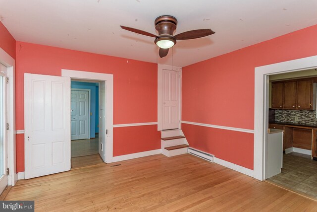 unfurnished room featuring ceiling fan, a baseboard radiator, and light wood-type flooring