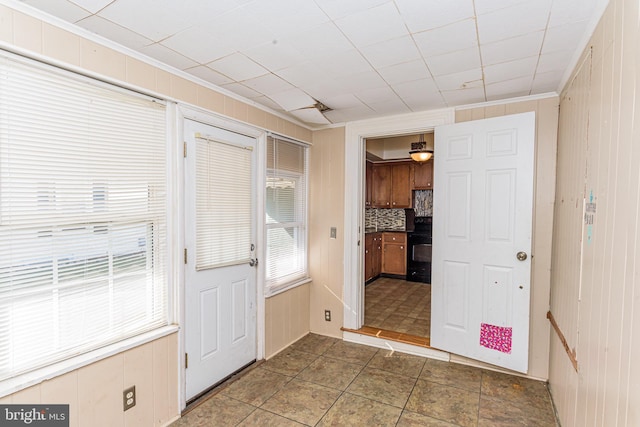 entryway featuring ornamental molding and wood walls