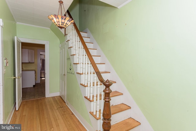 staircase featuring crown molding and hardwood / wood-style flooring