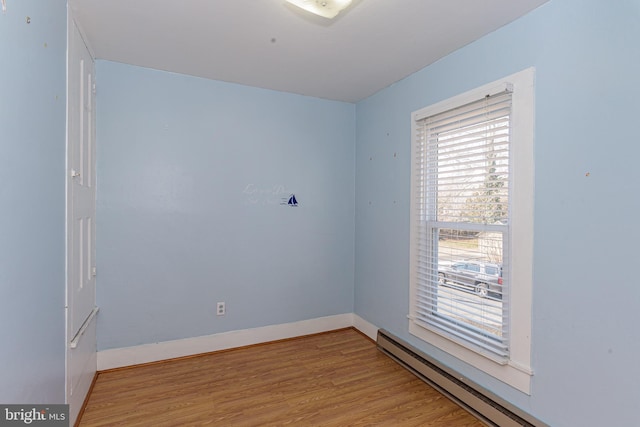 unfurnished room featuring a baseboard radiator and light hardwood / wood-style floors