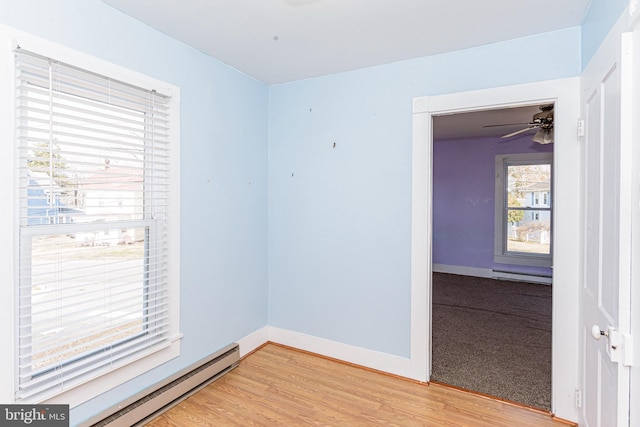 spare room with hardwood / wood-style flooring, ceiling fan, and baseboard heating