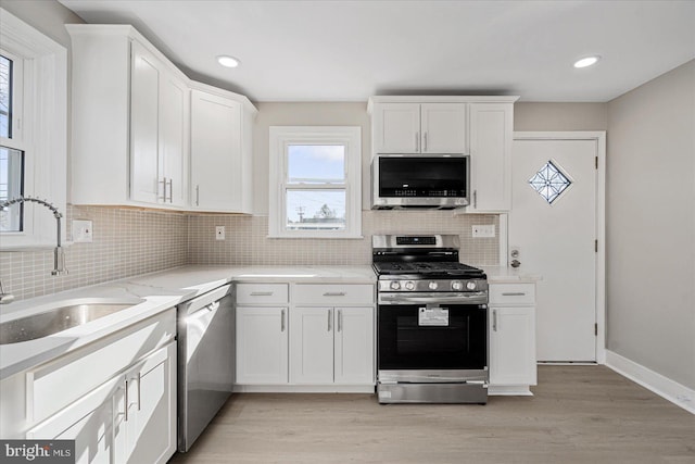 kitchen featuring stainless steel appliances, sink, light hardwood / wood-style floors, and white cabinets