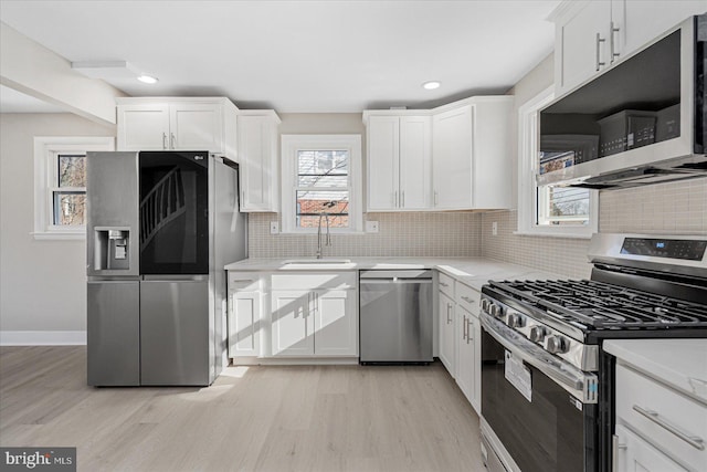 kitchen featuring white cabinetry, sink, light wood-type flooring, and appliances with stainless steel finishes