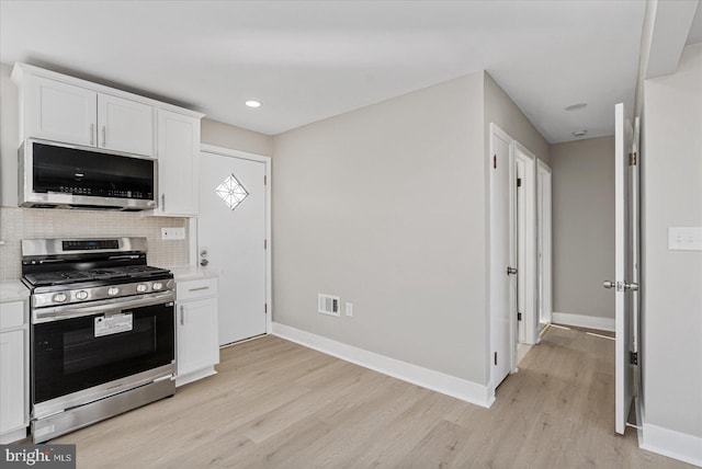 kitchen with stainless steel appliances, white cabinetry, light wood-type flooring, and decorative backsplash