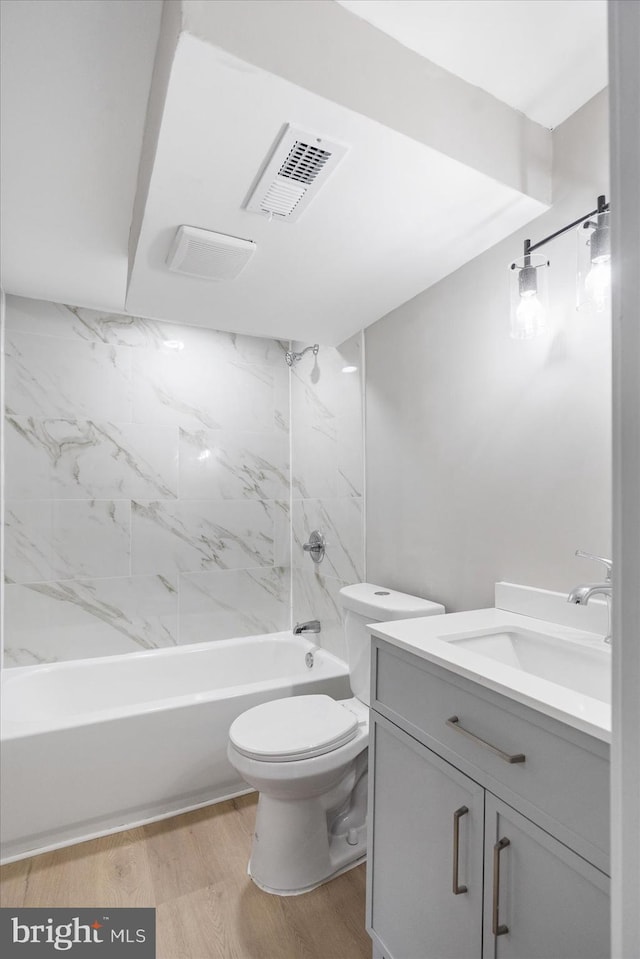 full bathroom featuring tiled shower / bath combo, wood-type flooring, vanity, and toilet