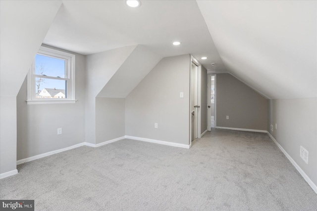 additional living space featuring vaulted ceiling and light carpet