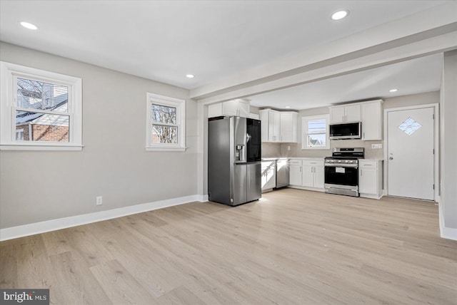 kitchen with white cabinetry, appliances with stainless steel finishes, light hardwood / wood-style floors, and decorative backsplash