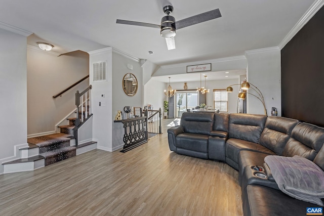 living room with hardwood / wood-style floors, ceiling fan with notable chandelier, and crown molding