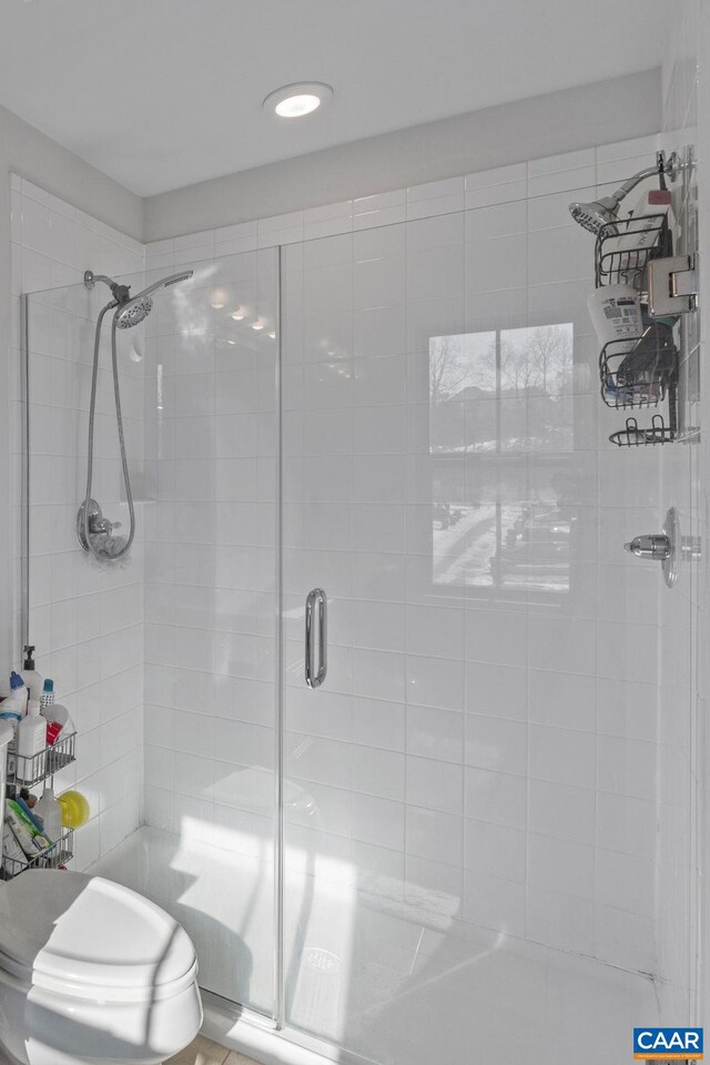 bathroom with a shower with door and toilet