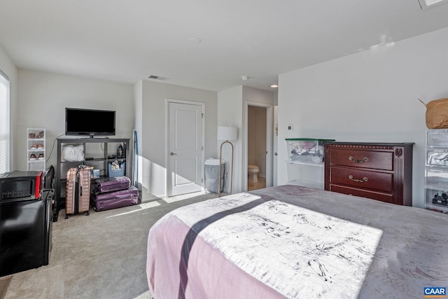 bedroom featuring ensuite bath and light carpet