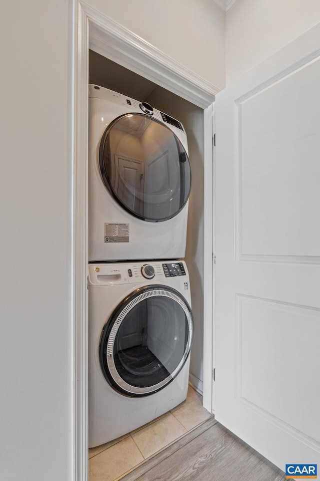 clothes washing area featuring stacked washer and dryer and light hardwood / wood-style flooring