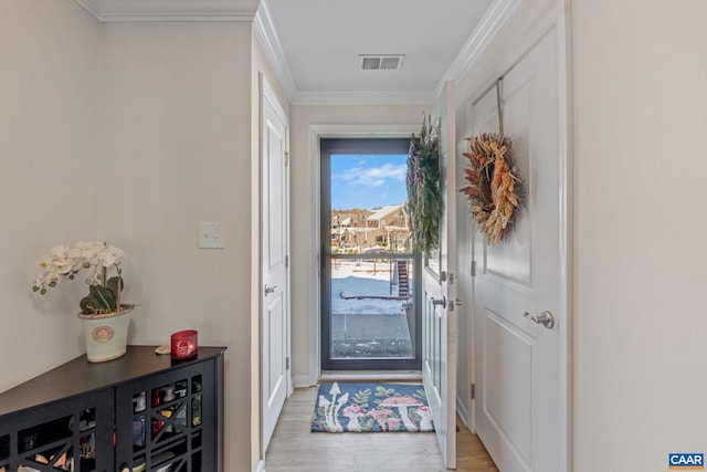 doorway to outside with light wood-type flooring and crown molding