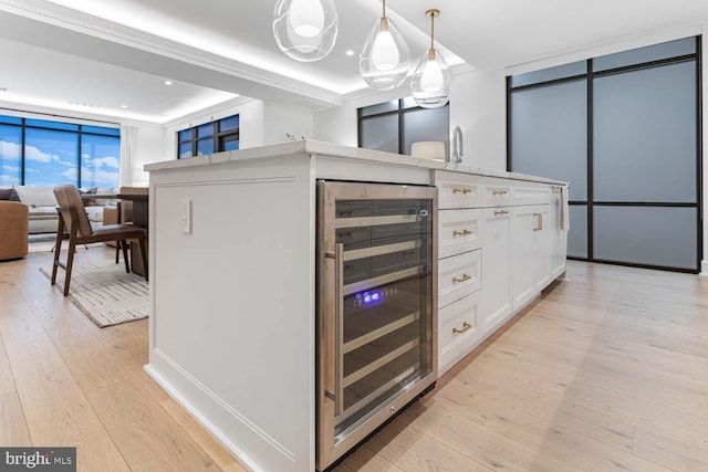 kitchen with sink, wine cooler, light wood-type flooring, decorative light fixtures, and white cabinetry