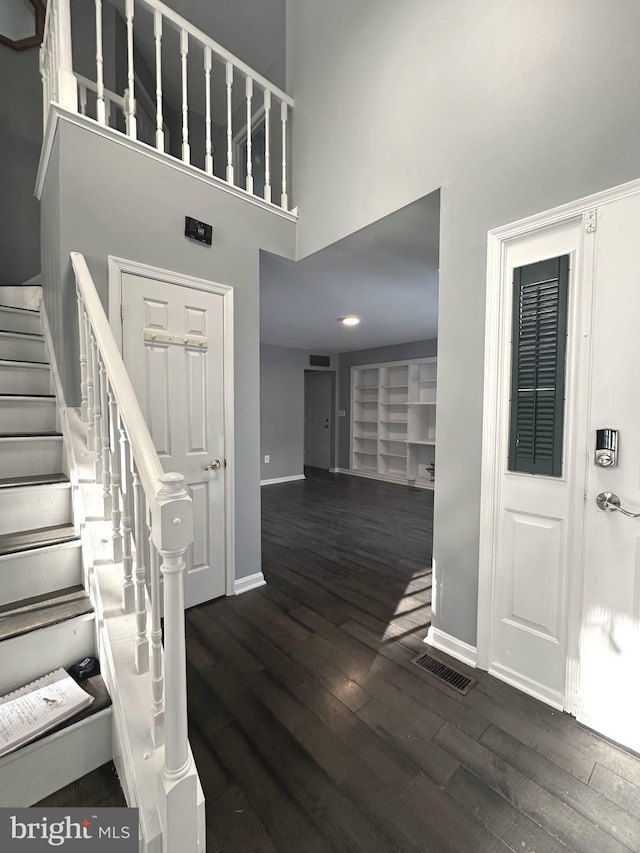 foyer with dark hardwood / wood-style flooring and a towering ceiling