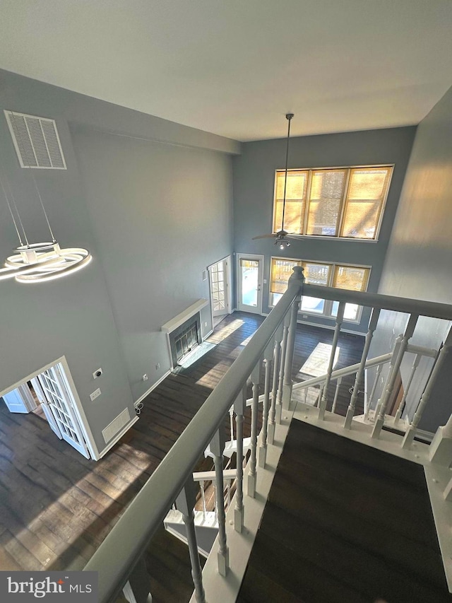 staircase with ceiling fan, hardwood / wood-style floors, and a towering ceiling