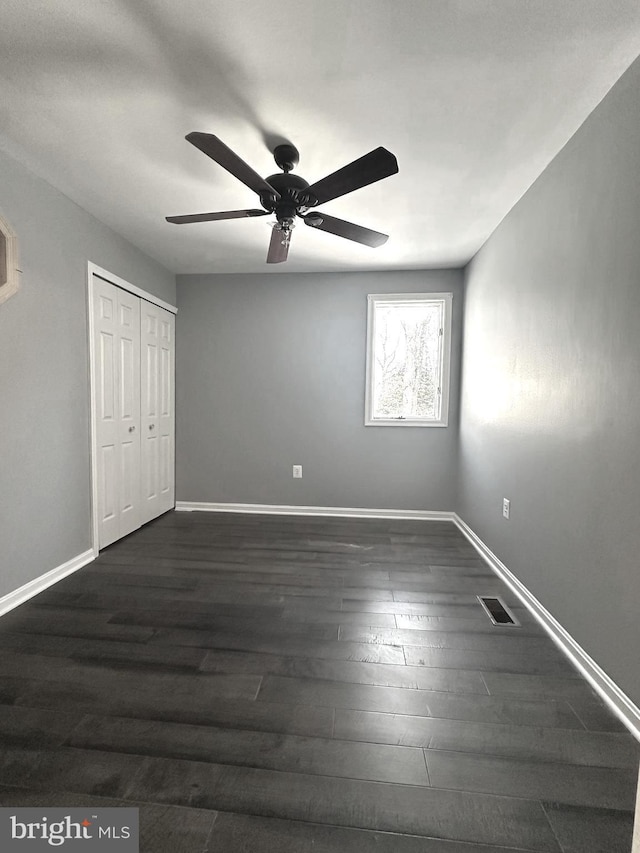 unfurnished bedroom with a closet, ceiling fan, and dark wood-type flooring