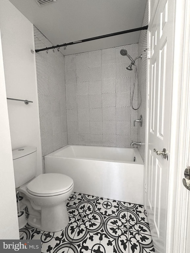 bathroom with tile patterned floors, tiled shower / bath combo, and toilet