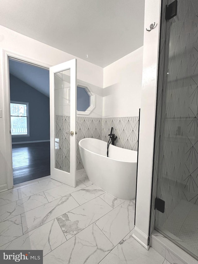 bathroom featuring separate shower and tub, vaulted ceiling, and tile walls