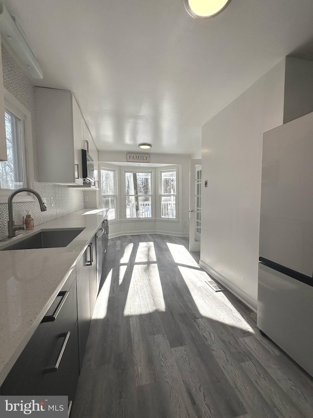 kitchen with light stone counters, sink, white cabinets, and plenty of natural light