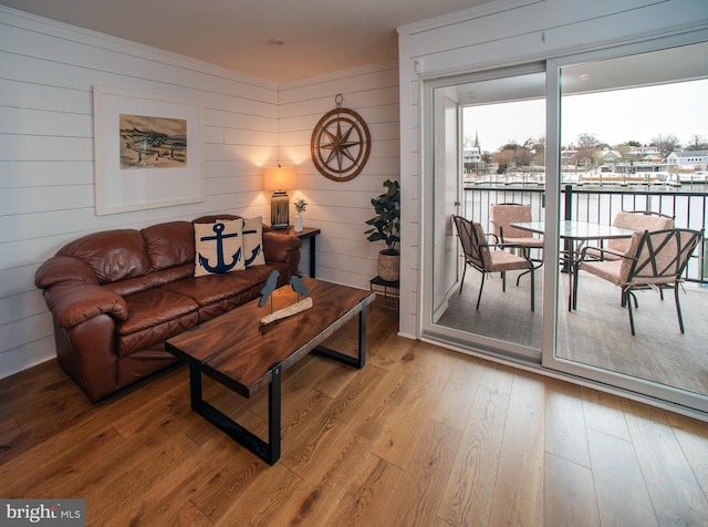 living room featuring light hardwood / wood-style flooring, a water view, and wooden walls