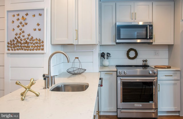 kitchen with light stone countertops, stainless steel appliances, tasteful backsplash, and sink