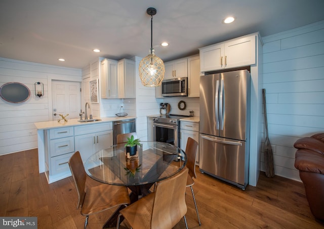 kitchen featuring pendant lighting, sink, dark wood-type flooring, appliances with stainless steel finishes, and white cabinets