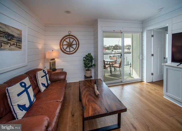 living room with light wood-type flooring and wood walls