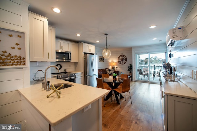 kitchen featuring white cabinetry, stainless steel appliances, decorative light fixtures, light hardwood / wood-style flooring, and sink