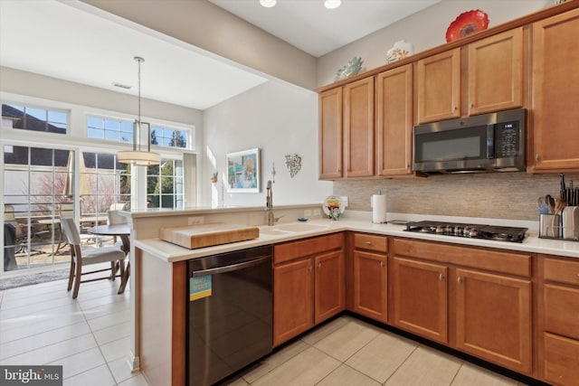 kitchen featuring kitchen peninsula, stainless steel appliances, decorative light fixtures, light tile patterned flooring, and sink