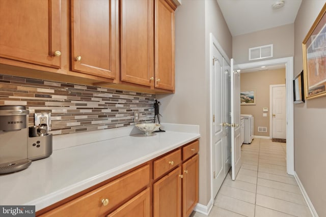 kitchen featuring washer and dryer, light tile patterned floors, and tasteful backsplash