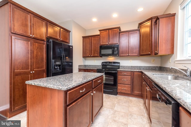 kitchen with light stone counters, plenty of natural light, a kitchen island, and black appliances