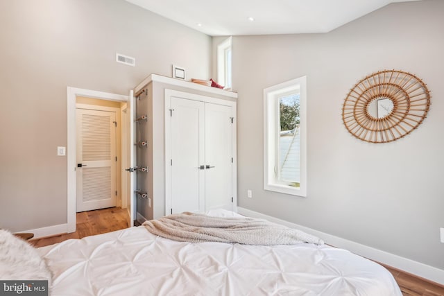 bedroom with light wood-type flooring and lofted ceiling