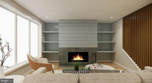 living room featuring a wealth of natural light, built in shelves, light hardwood / wood-style flooring, and a tiled fireplace