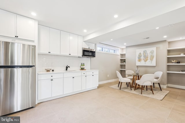 kitchen with stainless steel appliances, tasteful backsplash, light tile patterned flooring, white cabinets, and sink