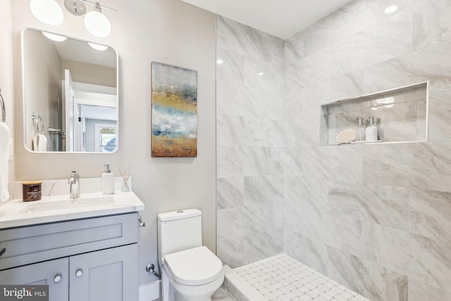 bathroom featuring toilet, vanity, and a tile shower