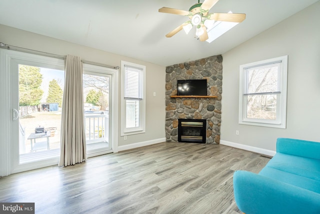 living room featuring ceiling fan, lofted ceiling, light wood-type flooring, and a fireplace