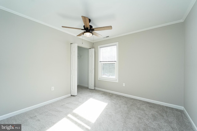 unfurnished bedroom with ceiling fan, light colored carpet, ornamental molding, and a closet