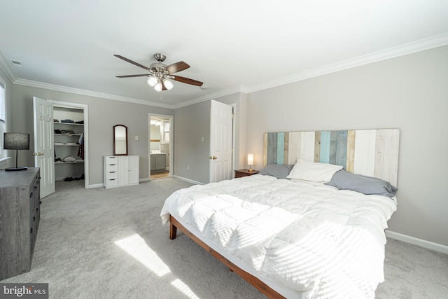 carpeted bedroom with connected bathroom, crown molding, a walk in closet, a closet, and ceiling fan