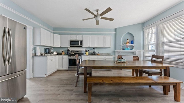 kitchen featuring ceiling fan, stainless steel appliances, light hardwood / wood-style floors, and white cabinets