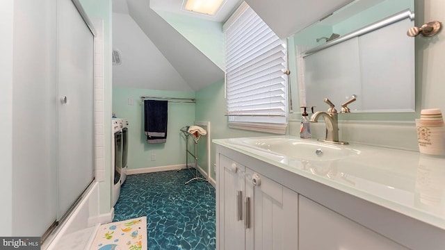 bathroom featuring vanity, bath / shower combo with glass door, washer and clothes dryer, and vaulted ceiling